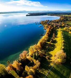 Starnberger See in Bayern mit Blick auf die Alpen und Segelboote auf dem Wasser.