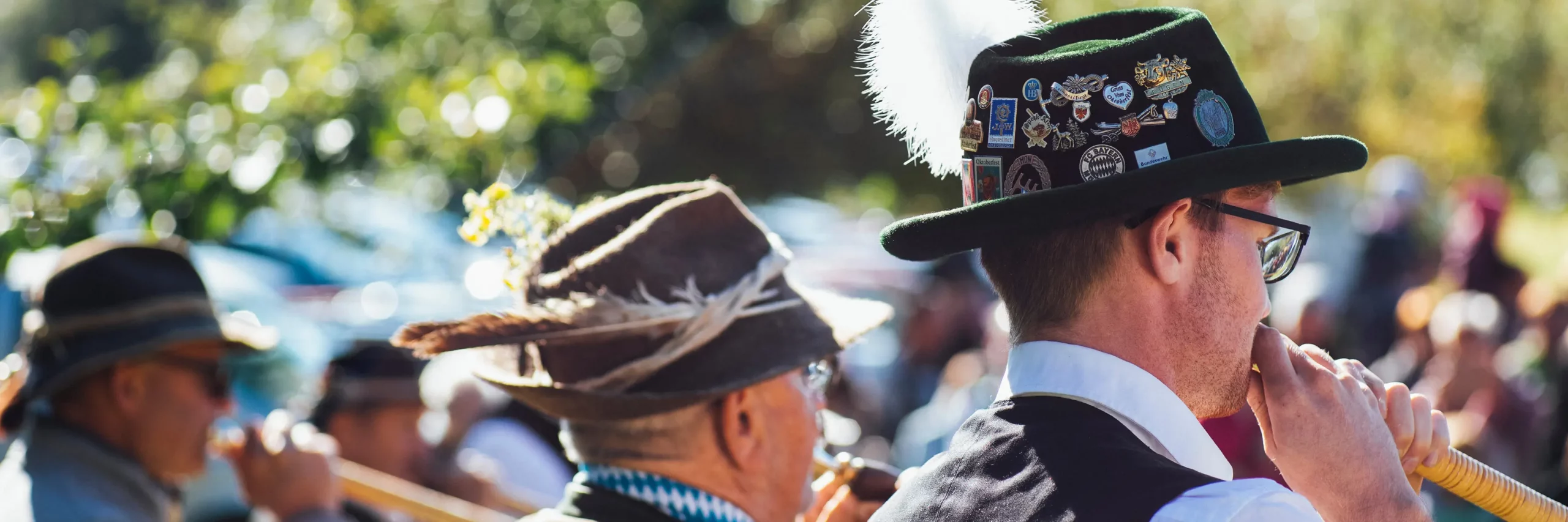 Menschen in bayerischer Tracht beim traditionellen Fest, mit Blasmusik und Schuhplattler-Tanz.