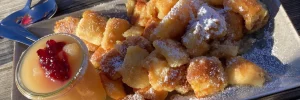 Ein Teller mit Kaiserschmarrn, bestreut mit Puderzucker und serviert mit Apfelmus.