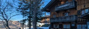 Die Speck-Alm in Sudelfeld, ein großes, ruhiges Haus auf dem Berg, umgeben von Bäumen und Schnee.