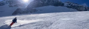 Eine Skifahrerin auf einer schneebedeckten Piste in Sudelfeld unter strahlend blauem Himmel.