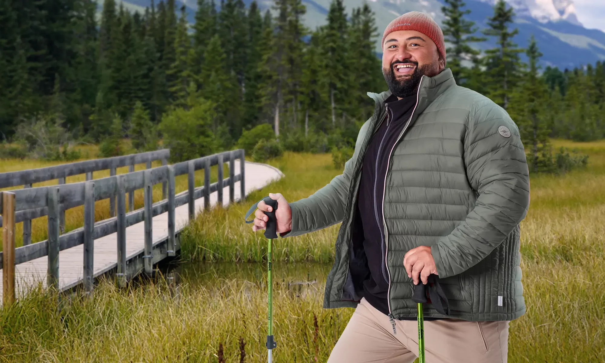 Mann mit Wanderstöcken steht am Fuße eines Berges, mit einer Brücke über einen Bach im Hintergrund.